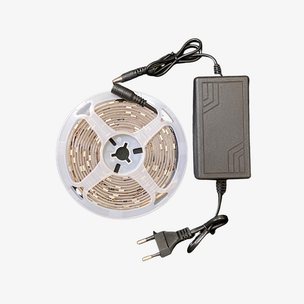 A 12 Volt Magic Strip LED light with a reel and an included power supply.