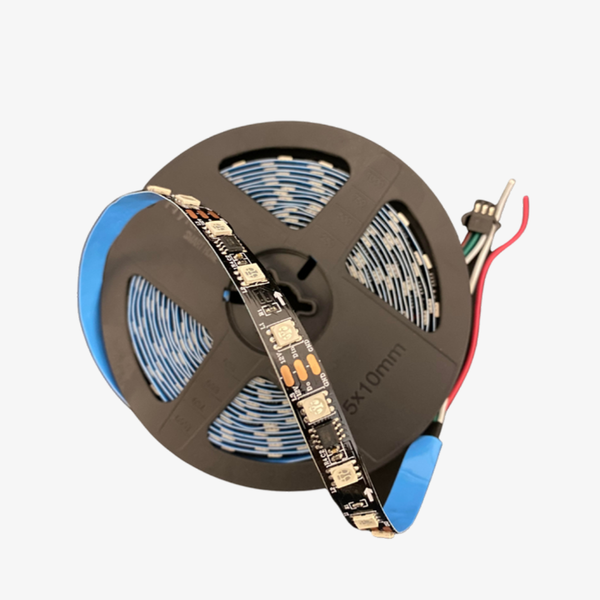 A roll of addressable pixel LED RGB strip with individual LEDs visible, alongside wires and a microcontroller chip.