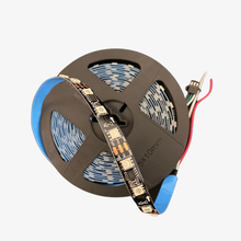 A roll of addressable pixel LED RGB strip with individual LEDs visible, alongside wires and a microcontroller chip.